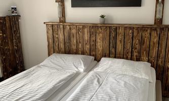 A cozy bedroom with two single beds and a rustic wooden headboard. A picture of a motorcycle hangs on the wall.