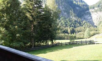A picturesque landscape with green meadows and dense forests. Majestic mountains rise in the background.