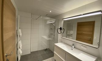 A modern bathroom with a glass shower and a bright vanity. The walls are in neutral colors, creating a calm atmosphere.