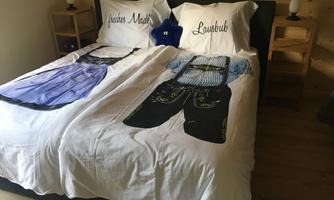 A bed with bedding that represents traditional Bavarian costumes. The pillows display the words "Madl" and "Lausbub".