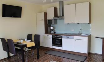 A modern kitchen with bright cabinets and a dining area. The space is well-equipped and pleasantly designed.
