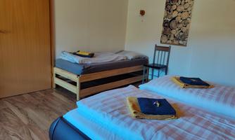 A simple room with two beds and a single bed. The walls are light, and there are decorative elements.