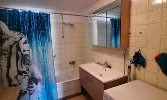A modern bathroom with a bathtub and a sink. The shower curtain has an interesting pattern in blue and white.