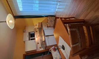 A cozy kitchen with a wooden dining area. There is a large table and windows that let in plenty of light.