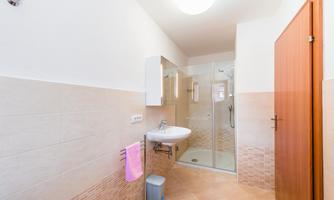 A modern bathroom with a shower, sink, and a large mirror. The walls are brightly tiled and the atmosphere is friendly and inviting.