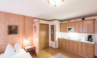 A cozy room with wooden walls and a sleeping area. The small kitchenette is modern and well-equipped.