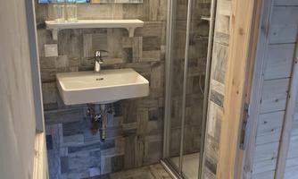 A modern bathroom with a shower, a sink, and a large wall mirror. The floor is designed with stylish tiles.