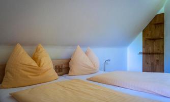 A cozy bedroom with a double bed and large pillows. The walls are light and the space feels inviting.