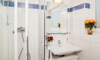 A modern bathroom with a shower and a sink. Fresh flowers in a vase are on the windowsill.