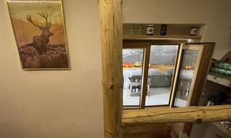 A cozy room with a window that looks out onto an outdoor area. On the wall hangs a picture of a deer in a golden frame.