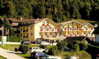 A picturesque hotel with blooming balconies and surrounded by trees. The beautiful courtyard invites you to linger.