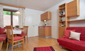A modern living room with a red sofa and a dining table. The large window front ensures plenty of daylight.