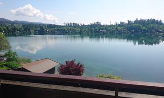 A peaceful lake with clear water and green shores. In the background, trees and hills are visible.