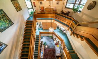 An open staircase with wooden railings and plants that leads to several levels. The walls are decorated with artworks.