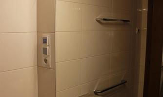 A modern bathroom with a sink and a large mirror. The walls are decorated with light tiles and there is bright lighting.