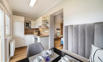 A modern kitchen with a dining table and stylish chairs. The bright walls and wooden floors create an inviting atmosphere.