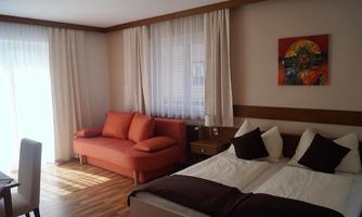 A cozy room with a double bed and a red sofa. Large windows provide plenty of daylight.