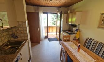 A bright kitchen with a dining table and chairs. The windows offer a beautiful view of the outdoors.