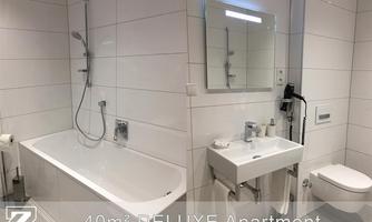 A modern bathroom with a bathtub, a sink, and a toilet. The walls are brightly tiled and the fixtures are elegant.