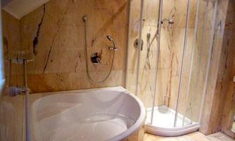 A modern bathroom featuring an elegant bathtub and a separate shower. The walls are adorned with marble-like tiles in warm tones.