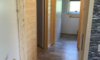 A bright hallway with wood paneling and a modern floor covering. In the background, two doors and a window are visible.