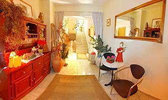 An inviting hallway with a red dresser, a small table, and a seating area. The walls are light, and there is a staircase leading to additional rooms.