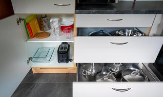 A modern kitchen with open cabinets. In the bottom area, pots, a toaster, and storage containers are visible.