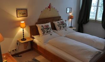 A cozy bedroom with a double bed and decorative pillows. The warm lamps create an inviting atmosphere.
