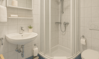A modern bathroom with a shower cabin and bright tiles. There is a sink, a toilet, and some towels.