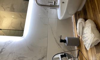 A modern bathroom with a stylish sink and a large mirror. Towels and toiletries are on the floor.