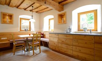 A cozy kitchen with wooden ceilings and modern furniture. The room is bright and inviting, with windows that let in plenty of daylight.