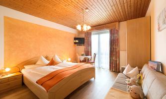 A cozy bedroom with a double bed and a bright, warm decor. A sofa and a large balcony with a view are also available.