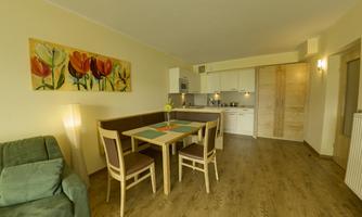 A bright and modern kitchen with dining area. The walls are decorated with a floral painting.