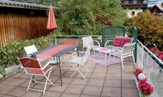 A cozy terrace with garden furniture and a sunshade. Surrounded by plants and flowers, ideal for relaxing afternoons.