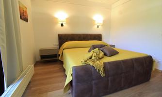 A cozy bedroom with a large bed and yellow bedding.  
Walls in neutral colors and warm light create an inviting atmosphere.