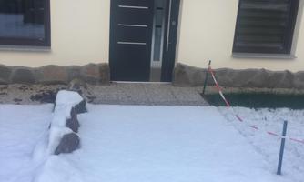 An entrance area with a modern door and fresh snow. The surroundings are calm and wintry.