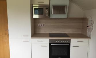 A modern kitchen with white cabinets and wooden surfaces. It is equipped with a stove, an oven, and a microwave.