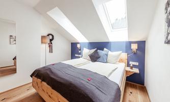 A modern bedroom with a double bed and cozy decor. Large windows provide plenty of daylight and an inviting atmosphere.