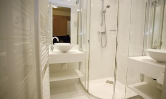 A modern bathroom with a clear glass shower and an elegant sink. The space is bright and designed in a minimalist style.