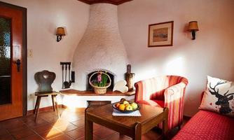 A cozy living room with an open fireplace and two comfortable sofas. On the table, there is a bowl of fresh fruit.