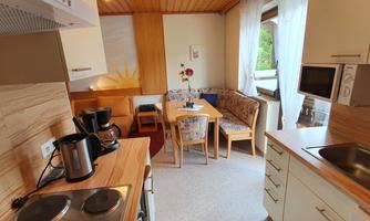 A modern kitchen with wooden elements and a dining area. The room is bright and inviting, with a cozy seating area.
