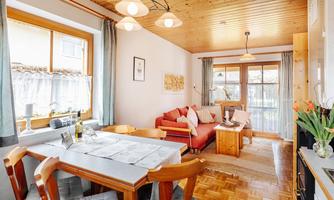 A cozy living space with a dining table and a red couch. Large windows let in plenty of light and create an inviting atmosphere.