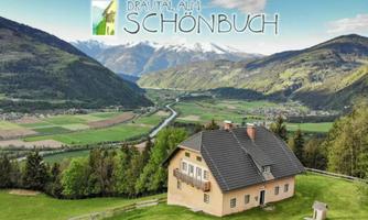 A picturesque mountain hut surrounded by green meadows and mountains. In the background, a clear river flows through the valley.