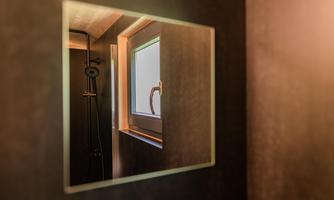 A mirror reflects a window in a bathroom. The scene is rendered in soft, warm colors.