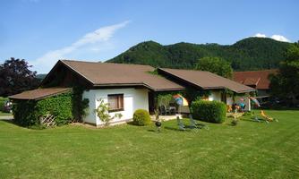 Two cozy holiday homes in a green environment. In the background, gentle hills and a blue sky can be seen.