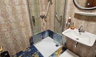 A modern bathroom with a shower and a sink. The walls are tiled, and the floor has a striking design.