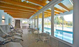 A bright interior with large windows overlooking a pool.  
Relaxed loungers are ready to enjoy the tranquility.