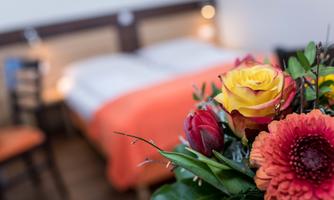 A cozy bedroom with an orange bed cover and delicate flowers in the foreground. The flowers give the room an inviting atmosphere.