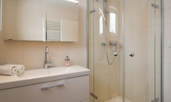 A modern bathroom with a glass shower and a white vanity. Towels are neatly arranged on the table.
