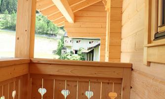 A wooden balcony with beautiful cladding and a view of the surroundings. The architecture is rustic and inviting.